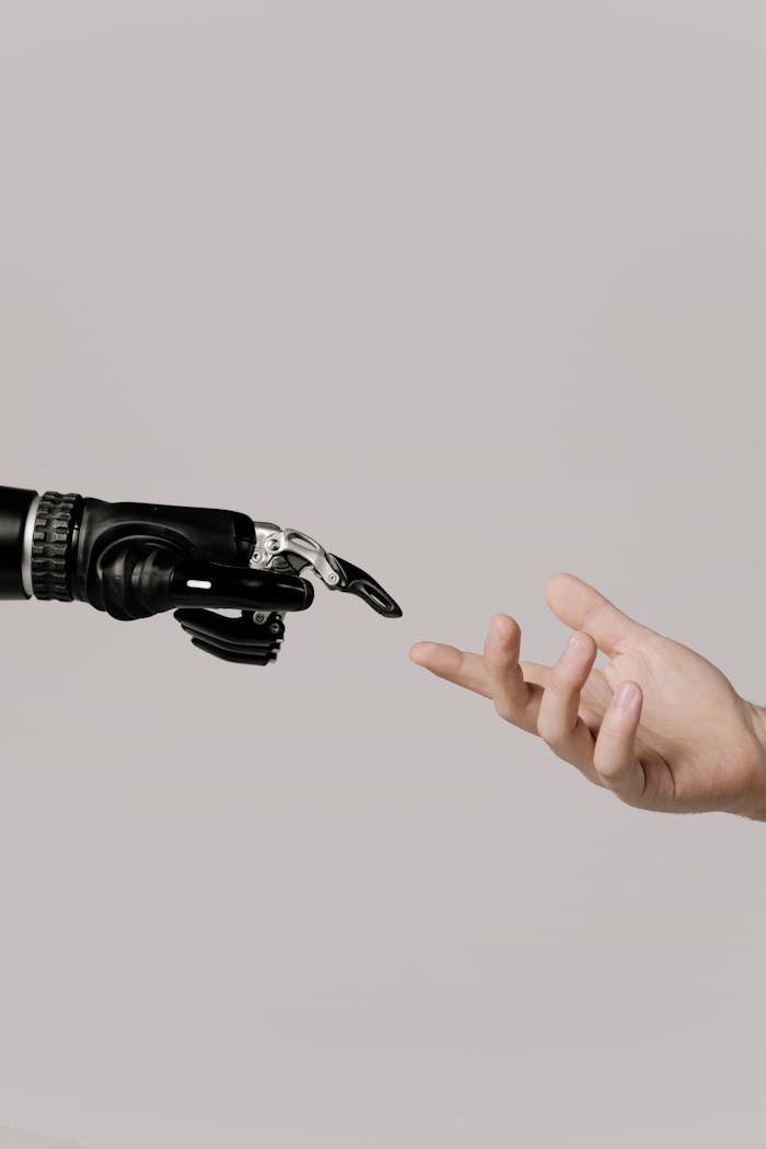 mobile-02 A human hand reaching to touch a bionic prosthetic hand on a white background.